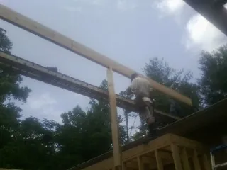 Carpenter setting a ridge beam over a new addition frame — Ice Dam Removal by Roofing Brothers in Ayden