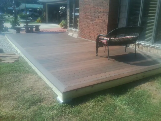 New wood deck and wicker chair beside a brick house in Ayden