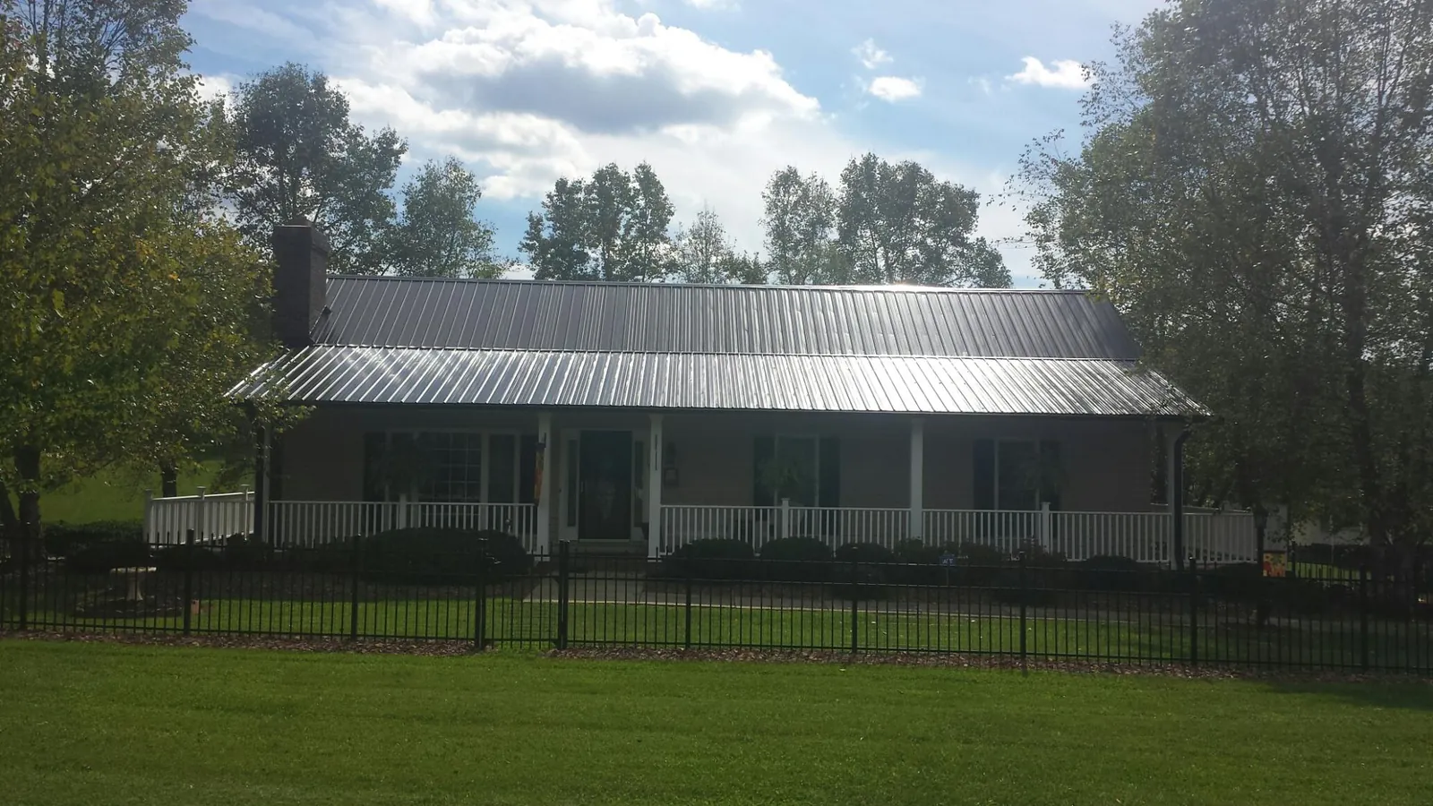 Gray metal roof on a brick ranch with a full width front porch — Gutter Guard Installation work by our crew in Ayden
