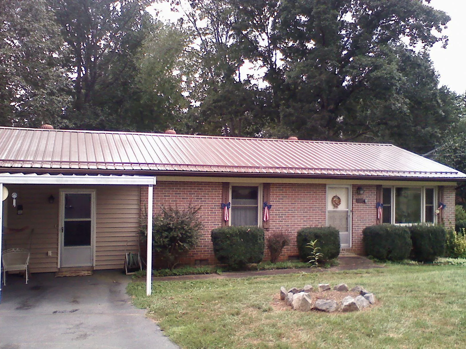 Bronze metal roof and carport on a brick ranch home — Roof Repair work by our crew in Ayden