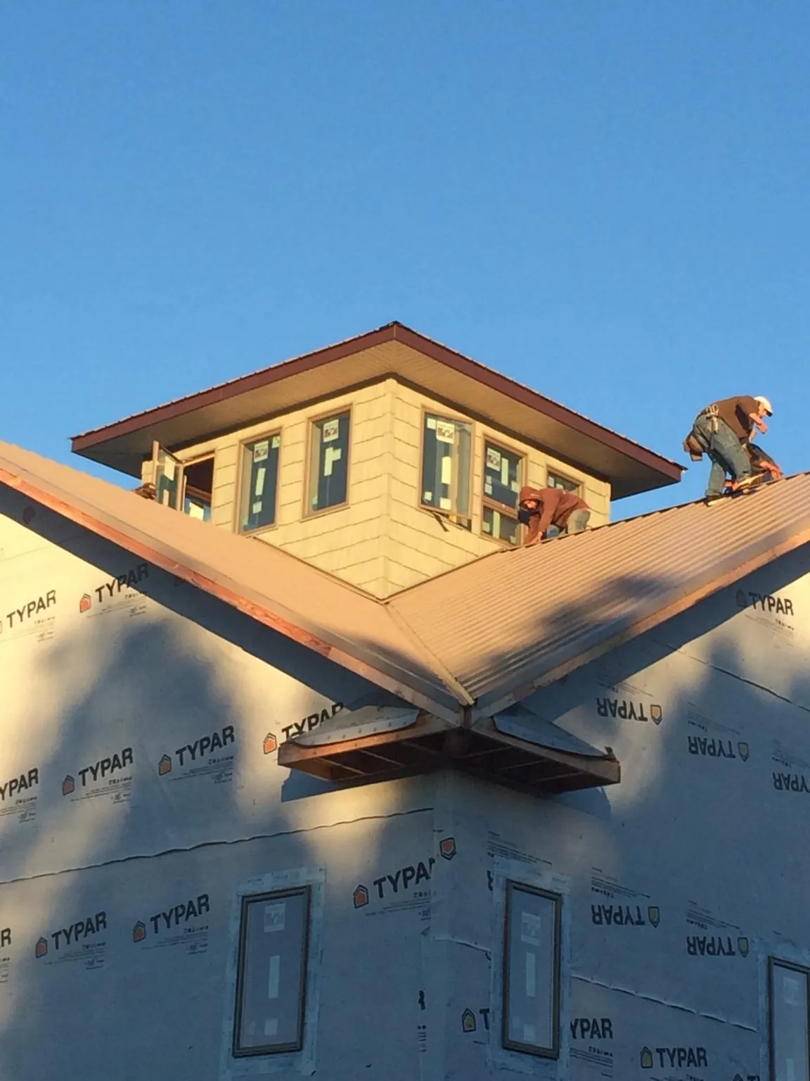 Roofers working around a rooftop cupola on a new metal roof at sunset — Roof Waterproofing in Ayden by Roofing Brothers